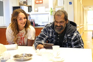 Jonge vrouw en oudere man zitten naast elkaar aan tafel