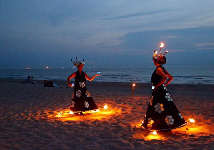 Twee vrouwen dansen met vuur op strand